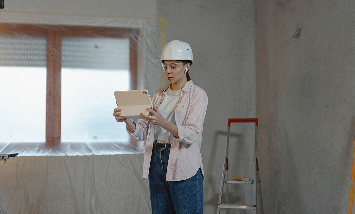 Femme photographiant un chantier avec une tablette