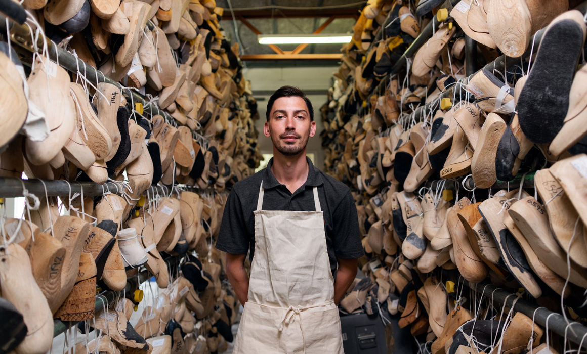 Artisan posant devant des rayons de chaussures