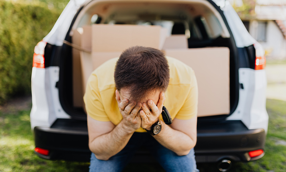 Homme accablé à l'arrière d'une voiture remplie de cartons