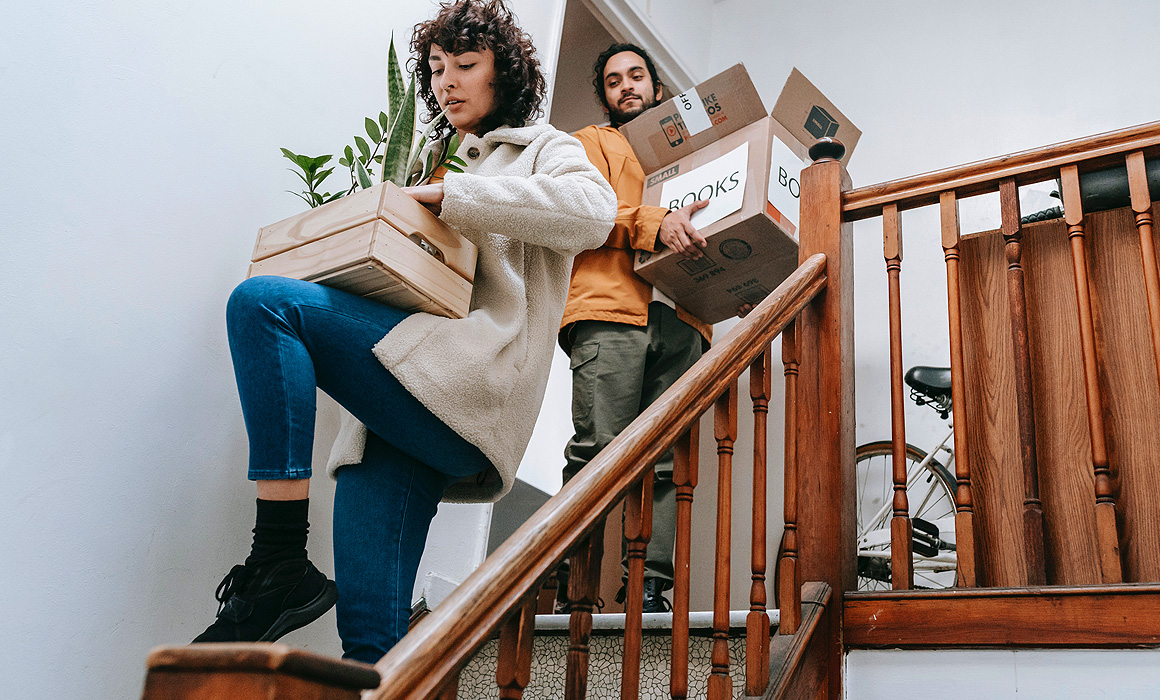 Couple portant des cartons dans un escalier