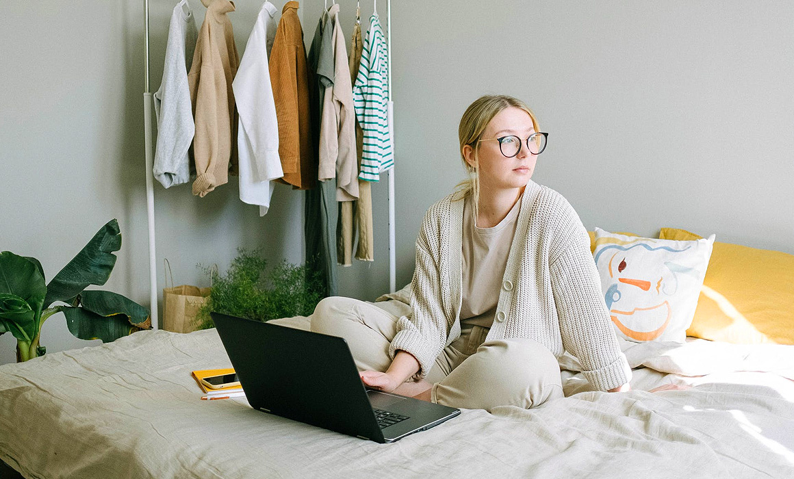 Femme avec ordinateur assise sur un lit
