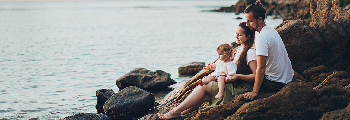 Famille assise sur des rochers en bord de mer